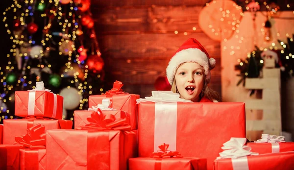 Feliz navidad. Concepto de infancia feliz. Niño llevar sombrero de santa celebrar envuelto caja de regalo de Navidad. Papá Noel me trajo regalos. Felicidad y alegría. Niño feliz chica emocionada encontrar regalos cerca del árbol de Navidad — Foto de Stock