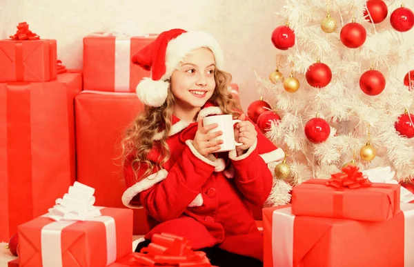 Niña linda niña sostener taza con bebida caliente mientras celebran la Navidad. Cacao caliente en Nochebuena. Bebida favorita de cacao. Kid santa hat disfrutar de la bebida de cacao. Manera perfecta de calentar la temporada de vacaciones —  Fotos de Stock