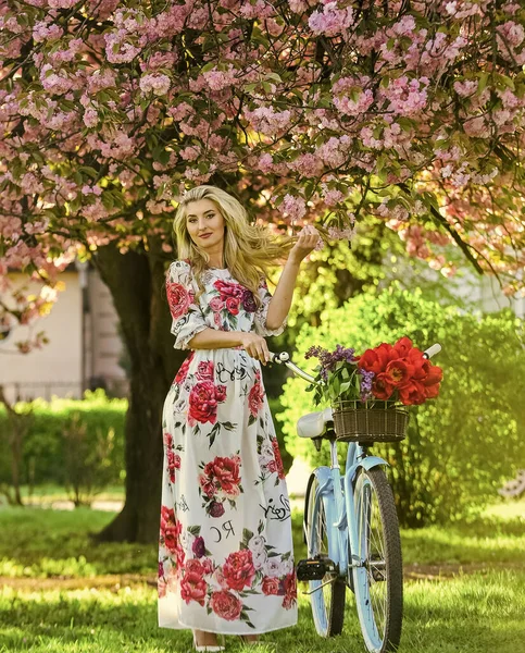 Příjemný jarní den. kvetoucí strom na jaře. přirozenou ženskou krásu. žena na zahradě. mladá módní dívka s retro kolo v blízkosti třešňových květů. dívka s ročníkem kolo v růžové sakura uličky — Stock fotografie