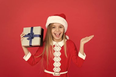 Yeni yıl için yeni ürün. Mutlu kız mala el kaldırıyor. Ürün sunan küçük bir kız. Ürün tanıtımı. Noel indirimi. Reklam metni için kırmızı arkaplan, kopyalama alanı
