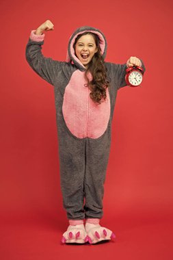 Kızgın çocuk uyumak için pijama giyiyor. Rahatlaman için kigurumi pijamaları. Tavşan pijamalı komik çocuk. Günün farklı saatleri ve çocuklar konsept programlar. Sabahleyin çalar saat