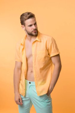 Sakin adam sarı arka plan pozu veriyor. Adam düğmesiz gömlek giyiyor ve göğsünde pürüzsüz deri var. Saç çıkarma prosedürü. Elbiselerini çıkar ve utanma. Erkek tüy dökücü göğüs.