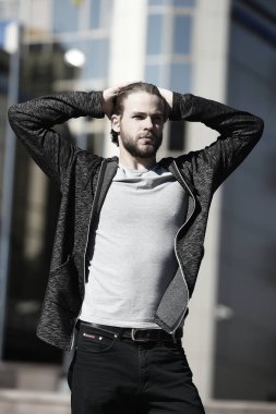 Sakallı adam elleriyle saçına dokunuyor.