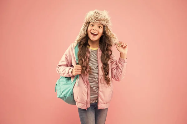 Férias de inverno. criança pano quente fundo rosa. chapéu earflap criança feliz. estudante com saco ir para casa. Fim do ano lectivo. Não há mais exames. pequena menina feliz de volta para a escola. Acreditar e ter sucesso — Fotografia de Stock