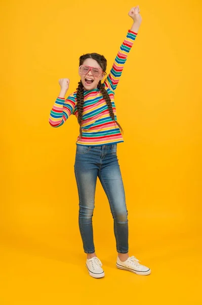 Vida ininterrupta. felicidade infantil. criança sorridente no fundo amarelo. acessório de moda casual. Hora da festa. menina adolescente feliz com penteado elegante. Miúdo engraçado a divertir-se. beleza em óculos de glamour — Fotografia de Stock