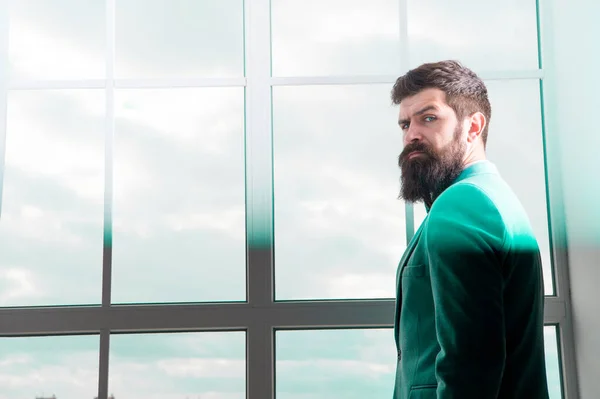 La vida moderna. hombre de negocios de pie en la ventana con paisaje urbano. Brutal hombre barbudo. Hipster maduro con barba. Hombre en la oficina de negocios moderna. Empresario en traje formal. La vida moderna del hombre de negocios — Foto de Stock