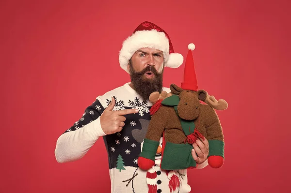 겨울 휴가. 크리스마스 준비 컨셉이야. 선물을 사. 겨울 쇼핑도 하고. 겨울 축제. 사슴 장난감이야. 산타 모자쓴 남자가 크리스마스 선물빨간 배경을 가지고 있어. 명랑 한 얼굴의 겨울 스웨터 — 스톡 사진