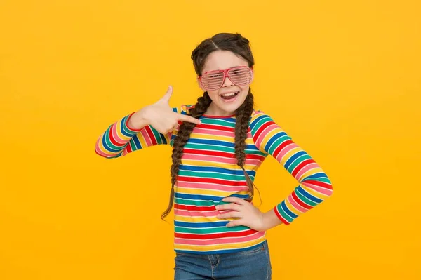Glücklich Teenager-Mädchen mit geflochtenen Haaren tragen lässigen Stil Regenbogenfarbe und Glamour-Party-Brille auf gelbem Hintergrund, positive — Stockfoto