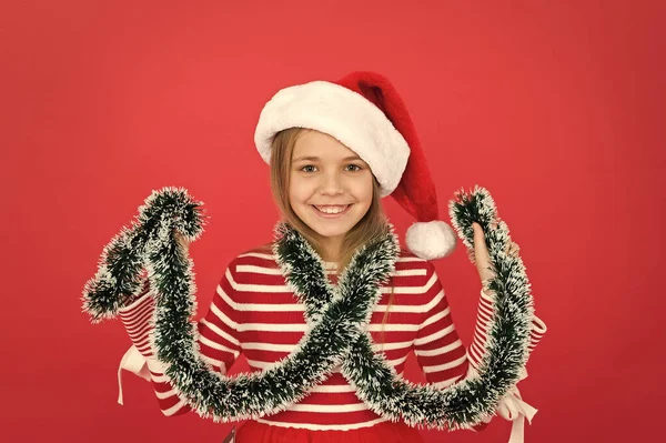 Small girl having fun. funny little id play with tinsel. santa kid with tinsel decor. xmas holiday decoration. time for christmas shopping. happy new year. festive party in red color. happy childhood — Stock Photo, Image