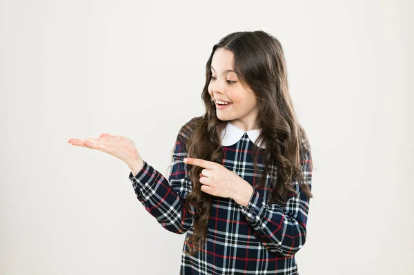 Présentation du produit. Petite fille belle coiffure. Cheveux longs et bouclés. Joyeux uniforme écolière élégant. Joyeux concept d'enfance. Joyeux portrait d'enfant souriant. Émotions expression émotionnelle. Regarde ça. — Photo