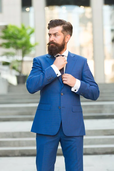 Серйозний директор з гіпсовою бородою фіксує краватку в офіційному костюмі на відкритому повітрі, формальний одяг — стокове фото