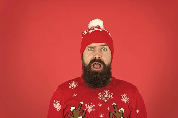 Está frio lá fora. atmosfera de férias de inverno. retrato de Papai Noel perplexo. Homem barbudo de chapéu fundo vermelho. hipster maduro em camisola de malha. usar roupas quentes nesta temporada — Fotografia de Stock