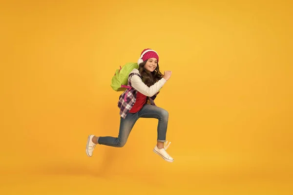 Está na hora de relaxar. pequena estudante correndo para a escola. Despacha-te com as férias. criança atrasada. sentido de liberdade. atividade infantil. menina ouvir música em fones de ouvido com mochila. voltar para a escola — Fotografia de Stock