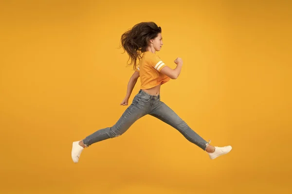 Przypływ energii. Energiczna dziewczyna w żółtym tle. Seksowna kobieta w energicznym ruchu. Porusza się w pośpiechu w energetycznym nastroju. Zwyczajny styl mody. Młoda i energiczna. Szybki, ale pełen wdzięku. — Zdjęcie stockowe