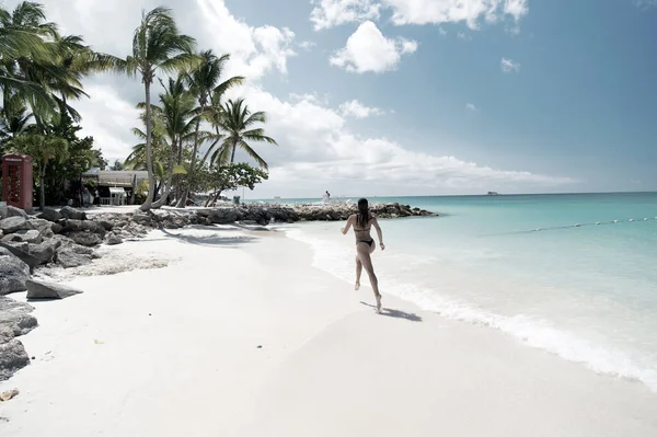 Mladá žena běží na tropické pláži — Stock fotografie