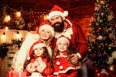 Mutlu bir anı yakalıyorum. Mutlu aile yeni yılı kutluyor. Portre seven aile. Bir sürü Noel hediyesi kutusu var. Mutlu noeller. Anne ve baba çocukları sever. Noel Baba şapkalı küçük çocuklar ve ebeveynler