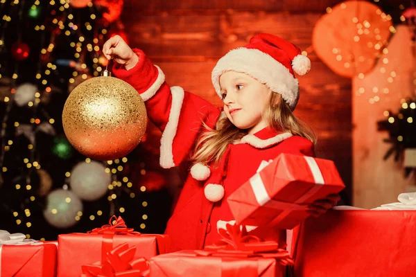 Tar fram julpynt för en festlig atmosfär. Små barn som håller julen glitter bollen dekoration. Liten flicka tittar på prydnad boll dekoration. Söt unge i jul inredning — Stockfoto