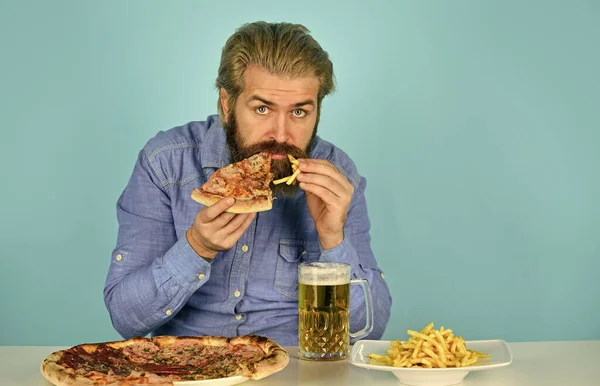 Cheers. watching football on TV. american fast food. happy bearded man with beer and pizza. italian food. French fries. guy in bar drinking beer glass and eating pizza