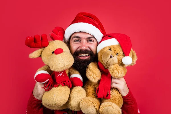 Homem barbudo feliz em chapéu de santa claus e camisola de malha com brinquedo comemorar o feriado de inverno do ano novo, presente de Natal — Fotografia de Stock