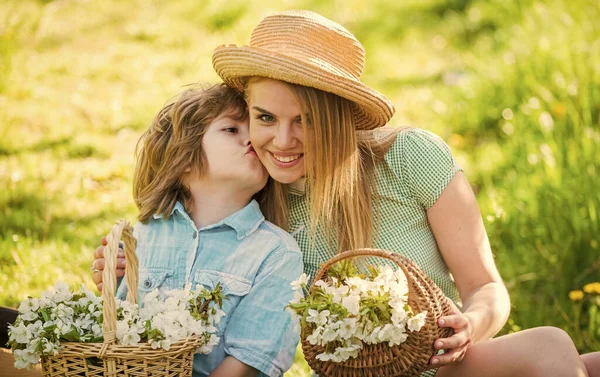 Happy holidays. Mother and cute son wear hats. Family farm. Spring holiday. Wildflowers in field. Motherhood happiness. Cowboy family collecting flowers in baskets. Lovely family nature background