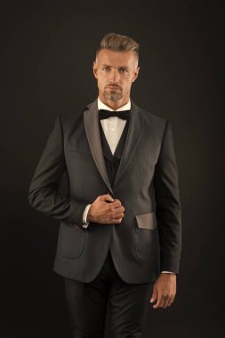 Klasikleri takdir ederim. Resmi görünüşlü sakallı adam. Hipster siyah arka plan. Smokin giymiş acımasız bir adam var. Klasik, insanı daha zeki gösterebilir. Siyah kravat. Moda dükkanı. Kıyafet al. Erkek giyim konsepti