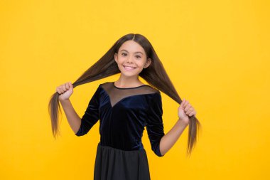 Kuaför olmak istiyorum. Mutlu kız uzun esmer saçları tutuyor. Kuaför salonu. Saç bakım kozmetiği. Sağlıklı saç ürünleri. Her çocuk için şampuan ve saç kremi. Temiz şeritler için güvenli köpükler