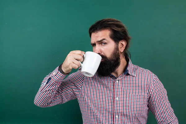 Maduro barbudo homem professor beber café na escola sala de aula com quadro-negro, de manhã — Fotografia de Stock