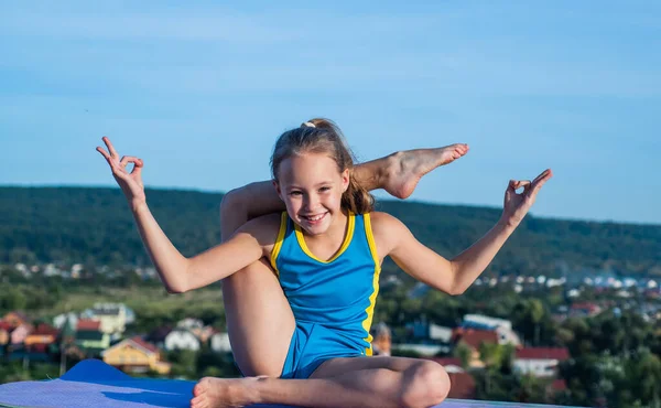 Gymnastik och yoga meditation. glad tonåring flicka på himlen bakgrund. Ungen har flexibel kropp. barn i sport kläder utbildning. stretcha och värma upp. barndoms lycka. hälsa och fitness — Stockfoto