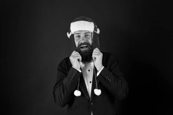 This hat warms his ears. Happy businessman wear santa hat. Bearded man smile in hat with earflaps and faux fur. Fashion accessory for Christmas. Warm and stylish trapper hat for santa party — Stock Photo, Image