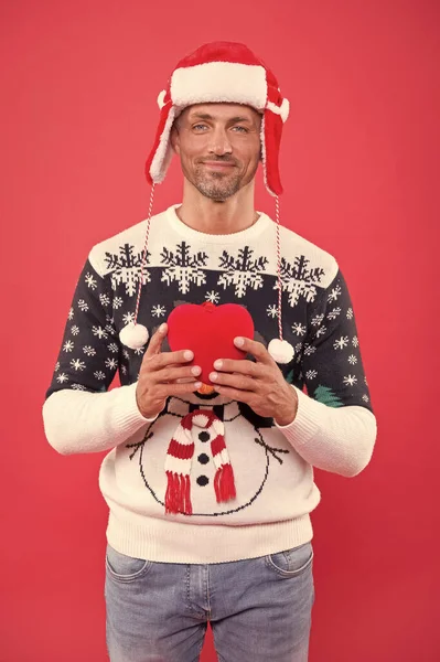 - Szeretlek. Jóképű ember ünnepli téli ünnepek piros háttér. A fickó téli pulóvert visel. Boldog karácsonyt és boldog új évet! Minden jót. Téli vakáció. Érett férfi kalapban mosolygós arc sörte — Stock Fotó