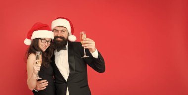 Köpüklü şarap. Ofis partisi. Ziyaret partisi töreni. Çift hazır şirket partisi. Mutlu yıllar. Sakallı beyefendi smokinli kız elbisesi giyer. Kırmızı arka plan. Mutlu Noeller.