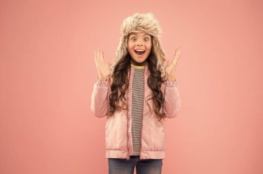 Bu ne sürpriz. Çocuk modası. Kız hipster gibi görünüyor. Mutlu çocuk pembe arka planı. Kürk şapka aksesuarı. Küçük kız kış kulaklığı. Sonbahar tarzı. Çocukluk aktivitesi. Soğuk mevsim için sıcak kıyafetler