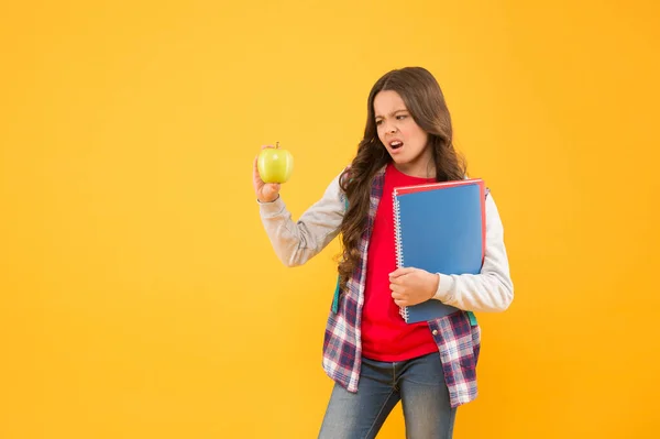 Jak se naučím rád jíst jablka. Nešťastné dítě drží jablečně žluté pozadí. Školní prázdniny. Zdravotní výchova. Organická svačinka. Rozvoj zdravých stravovacích návyků. Přírodní strava — Stock fotografie