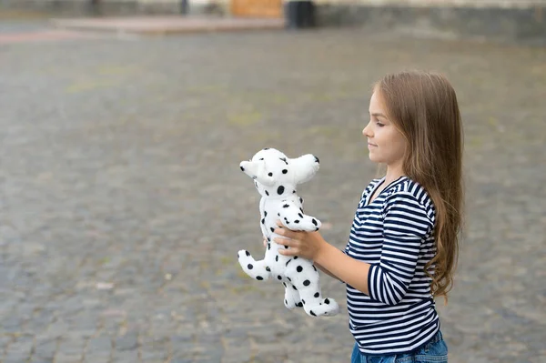 Criança com cabelo comprido em estilo casual jogo de moda com cão de brinquedo ao ar livre, loja, espaço de cópia — Fotografia de Stock