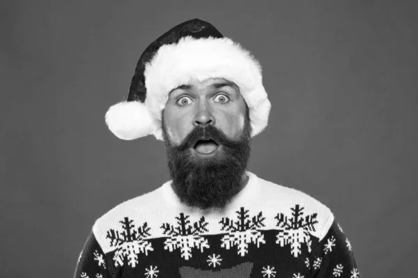 New year party. Unexpected surprise. surprised bearded man santa hat. brutal hipster favorite sweater red background. winter holiday fun. surprised face mustache. portrait of santa man with beard — Stock Photo, Image