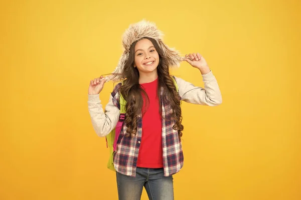 Som min stil. Inga lektioner den här veckan. Glada barn elev. vinterevenemang i skolan. liten flicka bära öronlapp hatt. vinter skoltid och helgdagar. Tillbaka till skolan. skolflicka ryggsäck gul bakgrund — Stockfoto