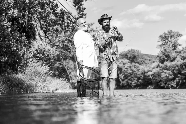 Disfrutando de la pesca del día. padre jubilado e hijo barbudo maduro. amigos hombres con caña de pescar y red. hobby del hombre de negocios. pesca de jubilación. pescadores felices. Buena ganancia. Aventuras de pesca con mosca —  Fotos de Stock