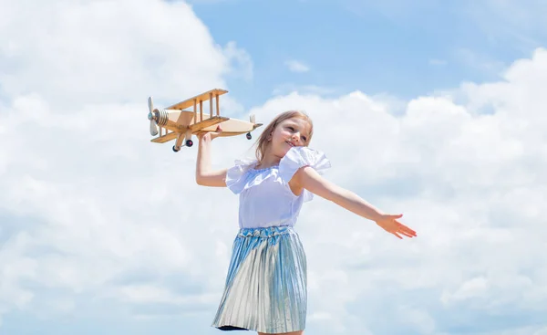 Avante para a aventura. adolescente menina jogar com avião de madeira. Estilo de moda infantil. conceito de viajar. infância feliz. criança bonito no fundo do céu. miúdo pronto para a viagem de férias. Vamos voar. carreira futura — Fotografia de Stock