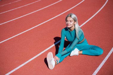 Esneme egzersizleri. Bayan sporcu spor için hazır. Antrenör ya da koç eğitimi. Mükemmel vücut şekli. sağlıklı ve sportif. Spor giyim bölümündeki seksi fitness kadını. Stadyumda esneyen atletik bayan.
