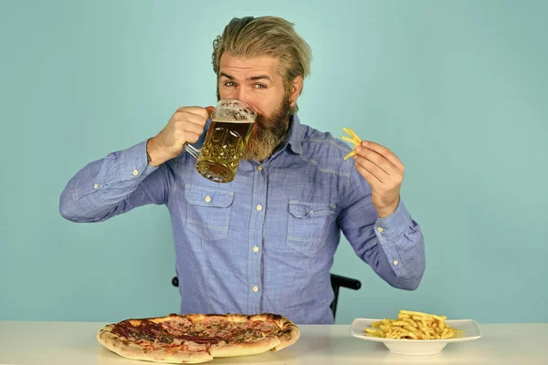 watching football on TV. american fast food. happy bearded man with beer and pizza. italian food. French fries. guy in bar drinking beer glass and eating pizza. Cheers