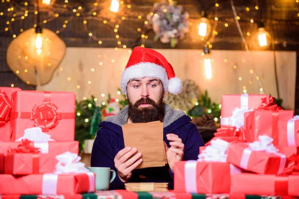 Hipster prepared gifts for family. Generous new year. Fulfill cherished dreams. Lot of gifts. Wrapped gifts with ribbons and bows. Happy winter holidays. Man bearded santa claus hat reading letters