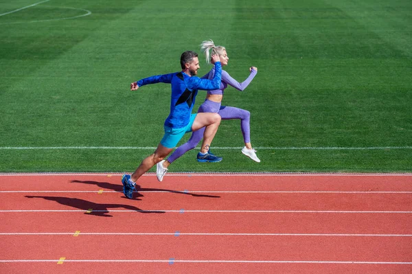 Hombre atlético y mujer sexy compiten en sprint. entrenador masculino y femenino en pista de atletismo del estadio. estilo de vida saludable. velocidad maratón. pareja de deportes corren rápido para ganar. velocistas de fitness exitosos — Foto de Stock