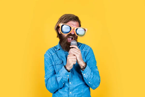 Hipster caucasico con barba e capelli eleganti in occhiali artistici con microfono, musica — Foto Stock