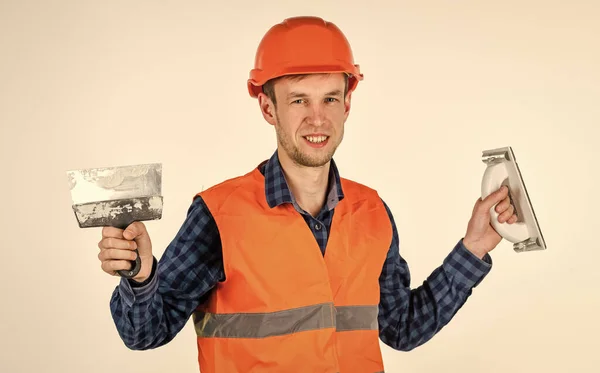 Trasferimento di esperienze. giovane lavoratore è assistente ingegnere. riparatore in uniforme. uomo usa lo strumento spatola. vero operaio edile in casco. falegname pronto a lavorare. attrezzature per la riparazione di utensili da costruzione — Foto Stock