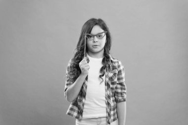 Kutlama. Mutlu küçük çocuk. Partiyi başlat. Eğlenmene bak. Elinde dürbünlü fotoğraf kabini destekleri tutan komik küçük kız. Süslü parti aksesuarları olan sevimli bir çocuk. Parti dekorasyonu. Parti dükkanı