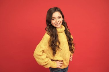 Kuaförden sonra mükemmel saç. Küçük güzel kırmızı arka plan. Güzel uzun kıvırcık saçlı kız. Mutlu küçük kız örgü süveter. Çocuklar için moda. Sonbahar ve kış sıcacık giysiler. Sıcak giyin her mevsim