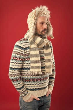 Erkek giyim konsepti. Moda koleksiyonu. Moda kıyafetleri. Örülmüş aksesuarlar. Soğuk kış koşulları. Şapka ve eşarp kırmızısı arka plan giyen yakışıklı sakallı adam. Kış modası. Isınıyorum. Sahte kürk