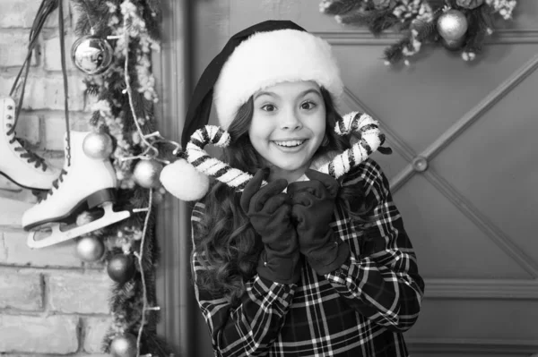 クリスマスの装飾。伝統的な冬の休暇を縞模様のキャンディー杖。帽子と手袋でエレガントな幸せな子供。サンタクロースを待っている。ペパーミントキャンディ。アイデアを飾る。子供はクリスマスの杖を持っている — ストック写真