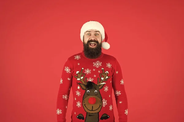 Check out my sweater. Happy new year. Join holiday party. Winter party outfit. Invitation ugly sweaters party. Sweater with deer. Hipster bearded man wear winter sweater and hat red background — Stock Photo, Image