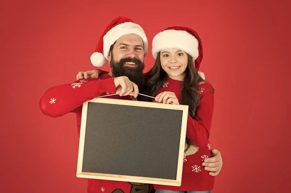 산타 클로스와 함께 크리스마스와 새해를 축하하 세요. 행복 한 가족은 빈 칠판을 가지고 있다. 산타를 둔 아버지와 딸은 빨간 배경을 가지고 있다. 산타 학교. 산타 파티에 함께 하시죠 복사 공간입니다 — 스톡 사진